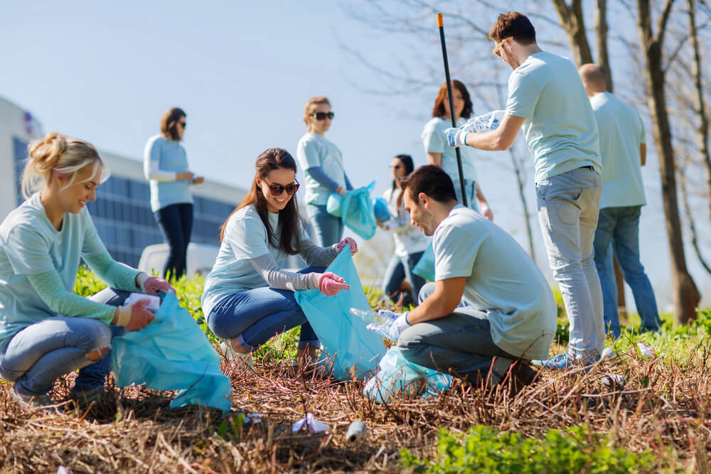 Grupa volontera sakuplja smeće na zelenoj površini
